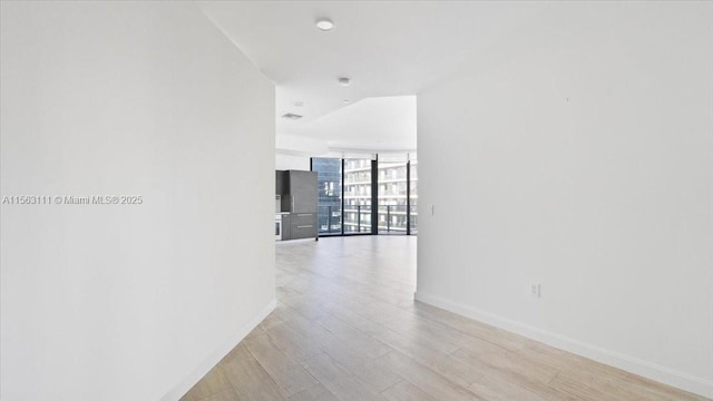 hall with floor to ceiling windows and light wood-type flooring