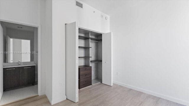 unfurnished bedroom with a closet, sink, and light hardwood / wood-style flooring