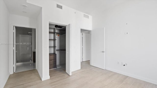 unfurnished bedroom with a walk in closet, connected bathroom, light hardwood / wood-style flooring, and a closet