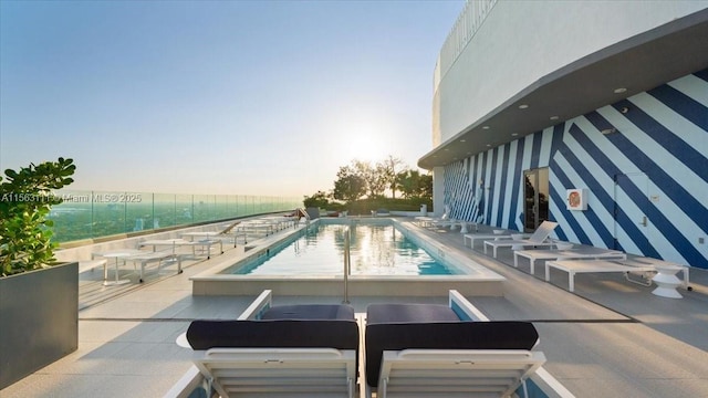 pool at dusk with a patio area