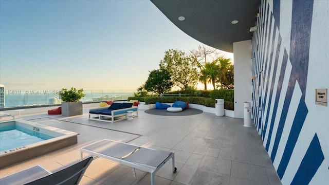 patio terrace at dusk featuring a water view