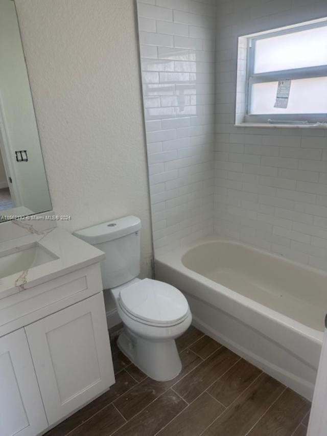 full bathroom featuring tiled shower / bath combo, toilet, and vanity