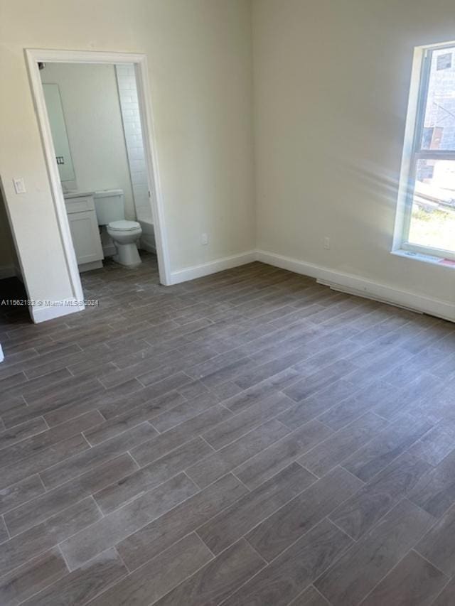 unfurnished bedroom with dark wood-type flooring and ensuite bath