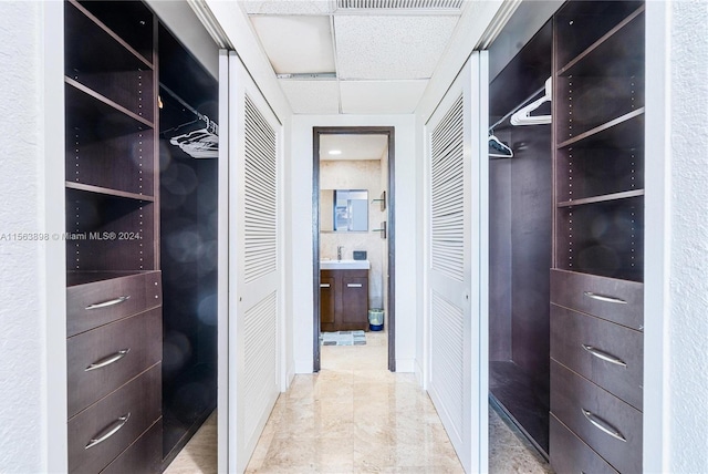 spacious closet with a drop ceiling, sink, and light tile floors