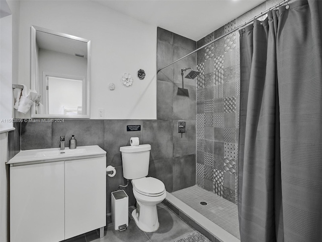 bathroom featuring curtained shower, toilet, vanity, tile walls, and tile floors