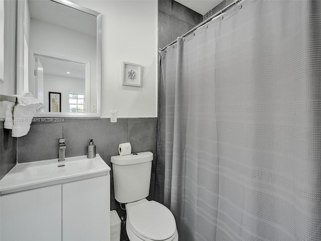 bathroom with vanity, backsplash, toilet, and tile walls