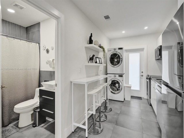 clothes washing area with light tile flooring and stacked washer and dryer