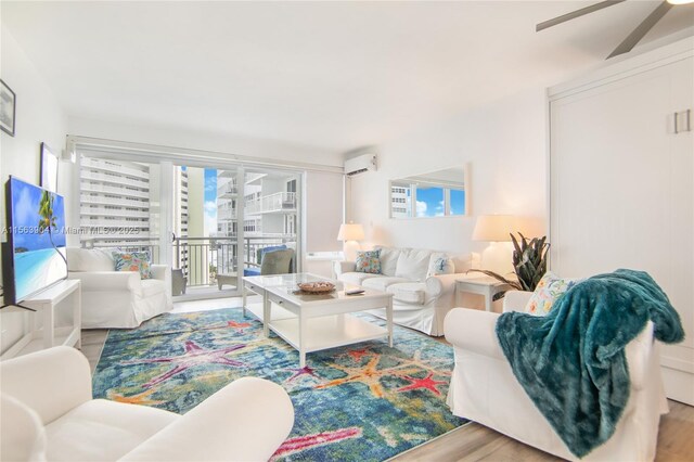 living room with a wall mounted AC, light hardwood / wood-style flooring, and ceiling fan