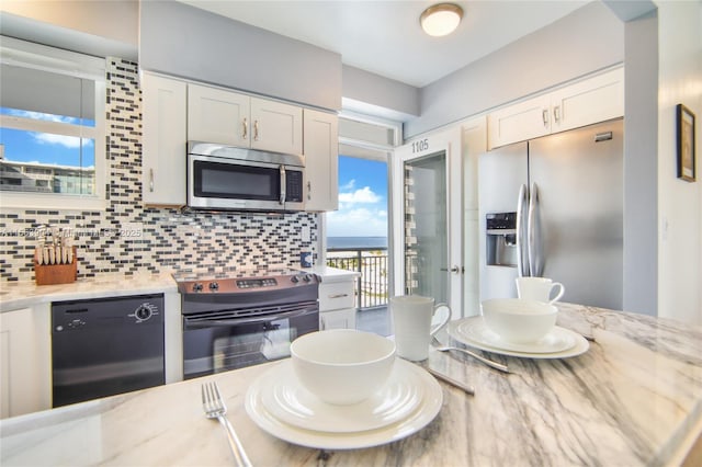 kitchen with stainless steel appliances, white cabinets, decorative backsplash, and light stone countertops