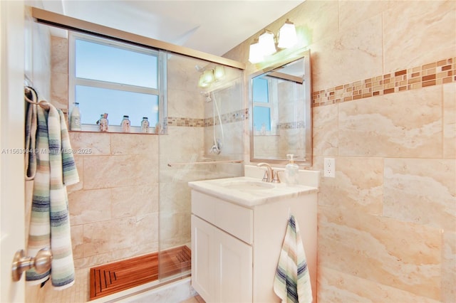 bathroom featuring tiled shower, vanity, and tile walls