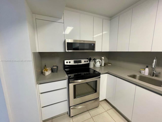 kitchen featuring light tile flooring, sink, stainless steel appliances, and white cabinets