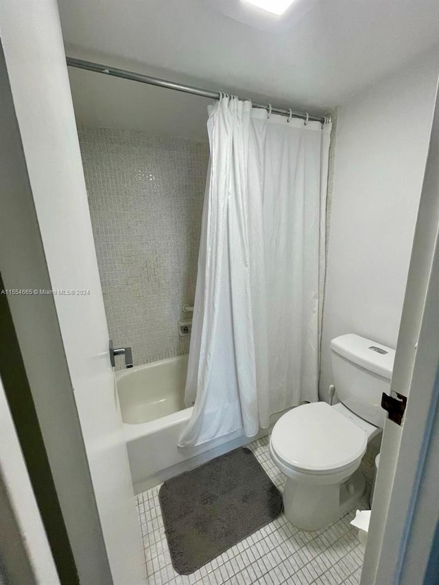 bathroom featuring toilet, tile floors, and shower / bath combo with shower curtain