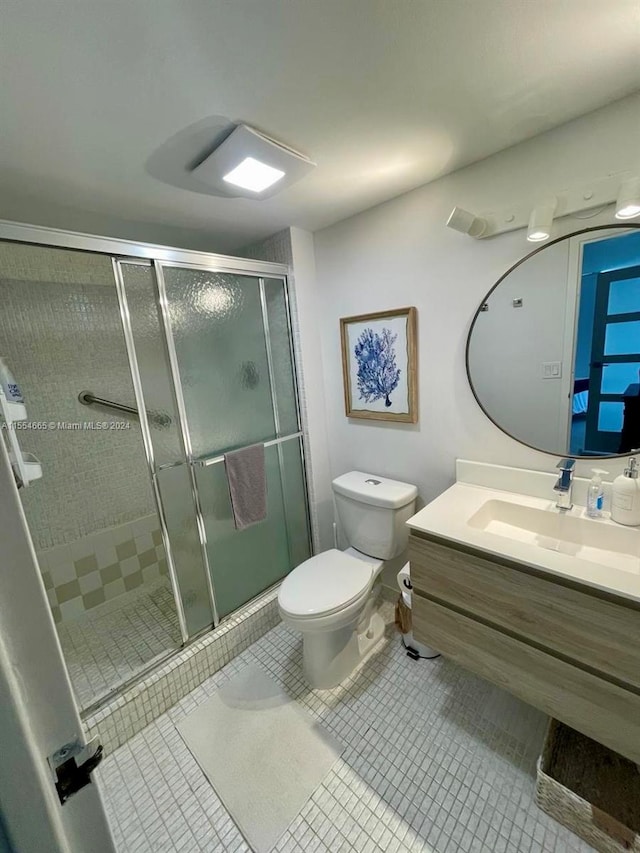 bathroom featuring vanity, a shower with door, tile flooring, and toilet