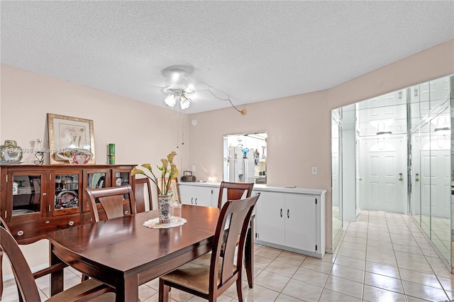 dining room featuring light tile floors, ceiling fan, and a textured ceiling