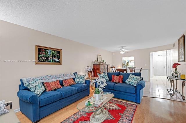 tiled living room featuring ceiling fan and a textured ceiling