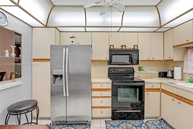 kitchen with ceiling fan, black appliances, sink, light tile floors, and cream cabinets