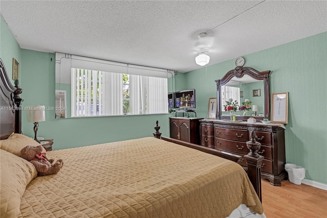 bedroom with light wood-type flooring, ceiling fan, and a textured ceiling