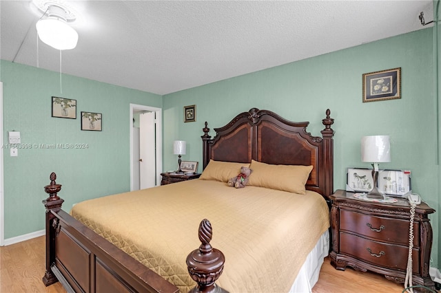 bedroom with light hardwood / wood-style floors and a textured ceiling