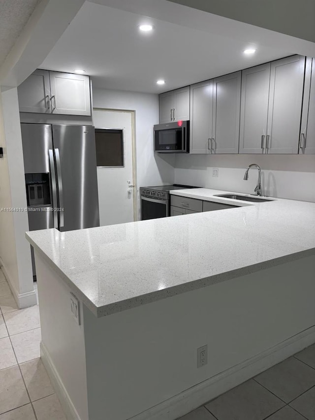 kitchen with kitchen peninsula, light stone countertops, light tile patterned floors, stainless steel appliances, and sink