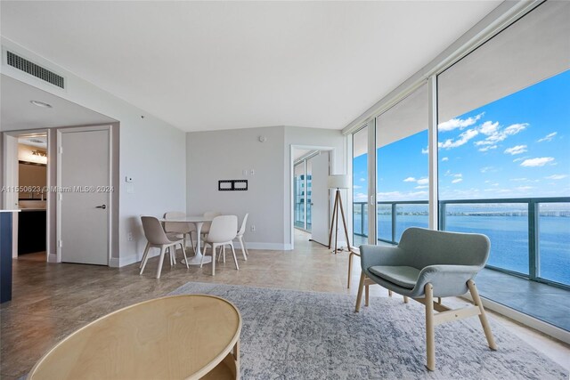 tiled living room featuring a water view and expansive windows