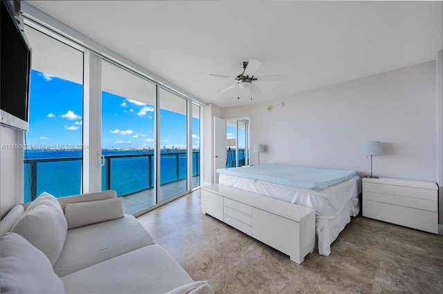 bedroom with floor to ceiling windows, ceiling fan, a water view, and access to exterior