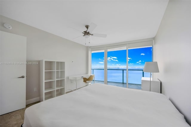 bedroom with access to exterior, expansive windows, ceiling fan, and a water view