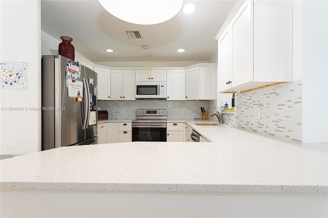 kitchen featuring light stone countertops, white cabinetry, backsplash, appliances with stainless steel finishes, and sink