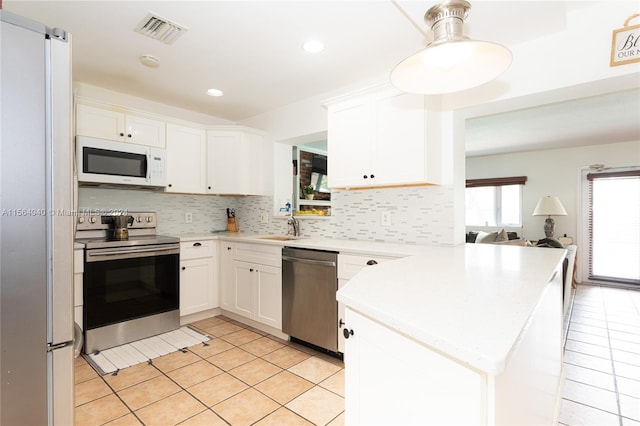 kitchen with white appliances, tasteful backsplash, and white cabinets