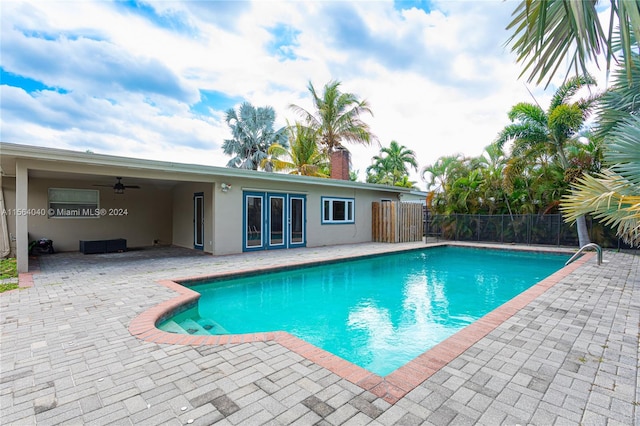 view of swimming pool with ceiling fan, a patio area, and french doors