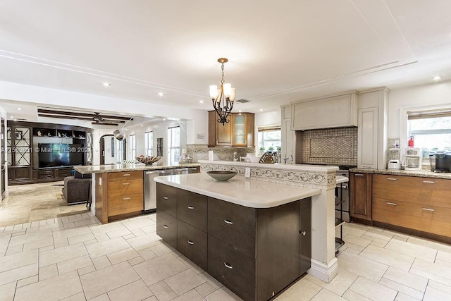 kitchen with a center island, pendant lighting, backsplash, ceiling fan with notable chandelier, and light tile flooring