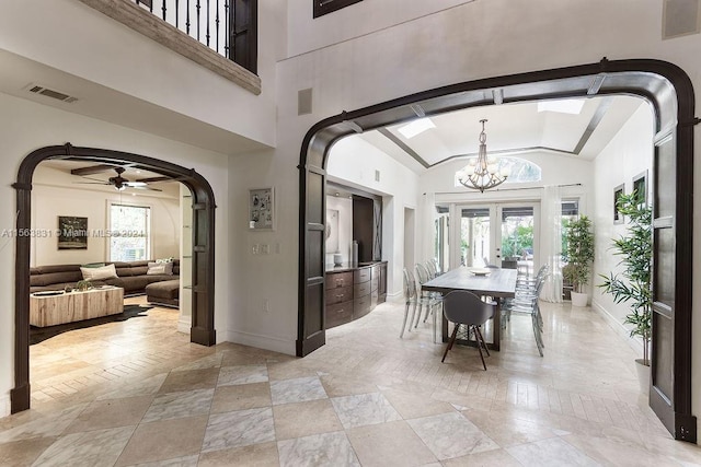 interior space featuring lofted ceiling, ceiling fan with notable chandelier, french doors, and a wealth of natural light