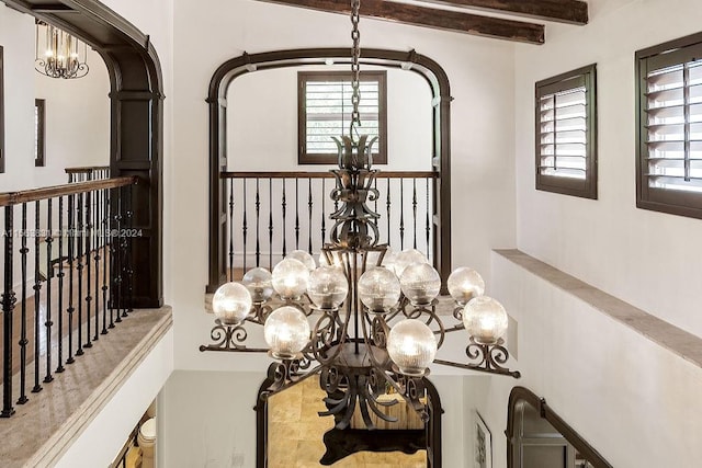 interior space with a notable chandelier and beamed ceiling