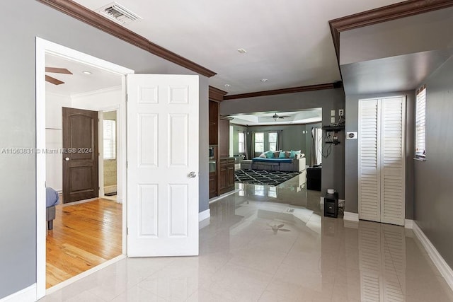 hall featuring light tile floors and ornamental molding