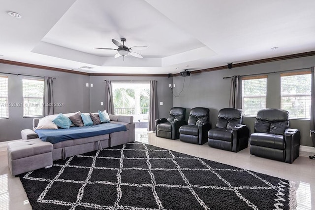 living room with ceiling fan, plenty of natural light, and a raised ceiling