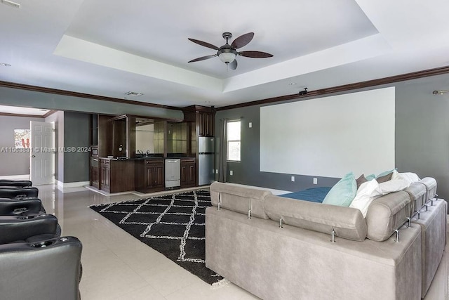 tiled living room with a tray ceiling, ceiling fan, and ornamental molding