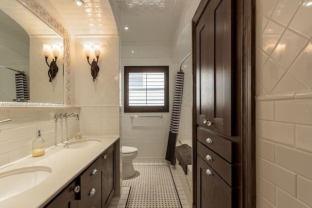 bathroom with tile flooring, tile walls, toilet, and dual vanity