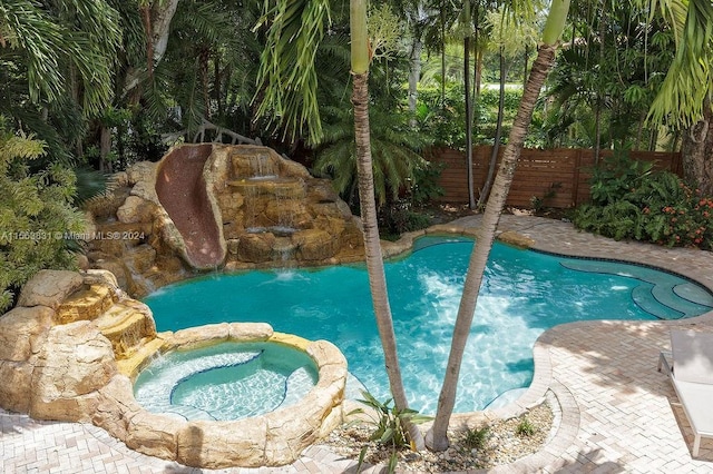 view of swimming pool featuring pool water feature and an in ground hot tub