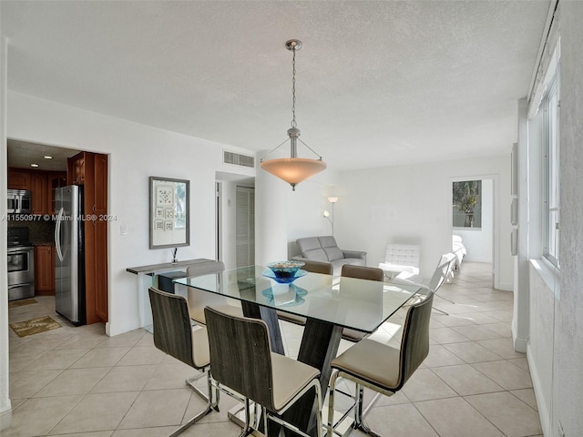 dining space with a textured ceiling and light tile floors