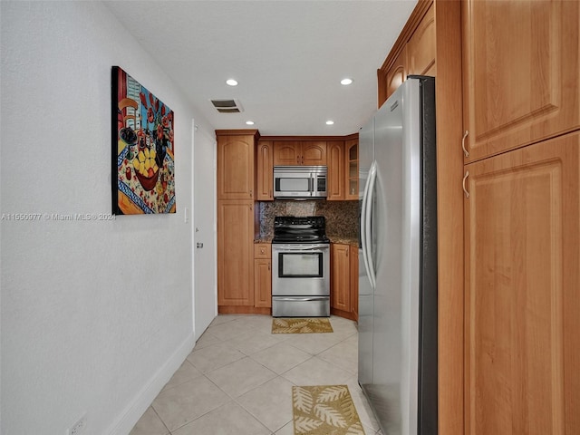 kitchen with dark stone counters, tasteful backsplash, light tile floors, and appliances with stainless steel finishes