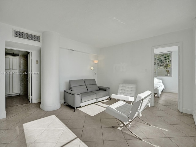 living room featuring decorative columns and light tile floors