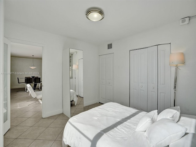 bedroom featuring two closets, light tile floors, and french doors