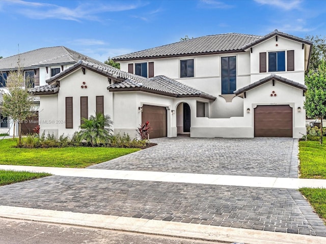 mediterranean / spanish house with a garage and a front lawn