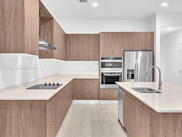 kitchen with wall chimney exhaust hood, sink, light tile patterned floors, and stainless steel appliances