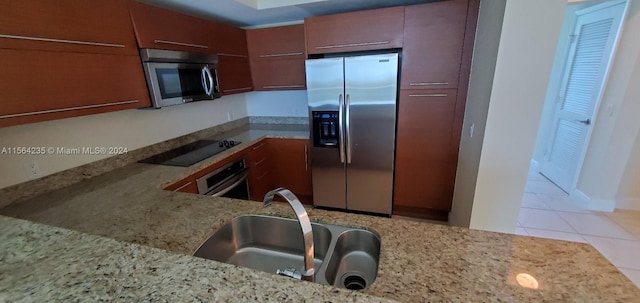 kitchen with light tile patterned floors, light stone countertops, appliances with stainless steel finishes, and sink