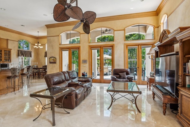 tiled living room with french doors, ceiling fan with notable chandelier, a high ceiling, and crown molding