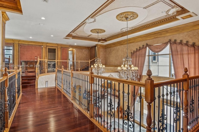 hall with hardwood / wood-style flooring, an inviting chandelier, ornamental molding, and a tray ceiling