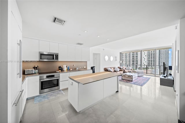 kitchen featuring a kitchen island, sink, white cabinetry, and stainless steel appliances