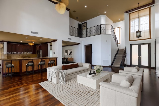 living room featuring ceiling fan, dark hardwood / wood-style flooring, a towering ceiling, and french doors