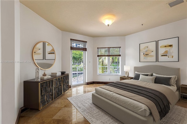 bedroom with access to exterior and a textured ceiling