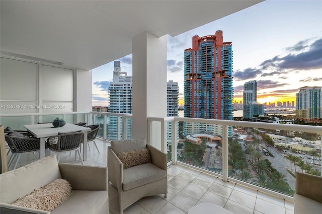 balcony at dusk featuring outdoor dining area and a city view